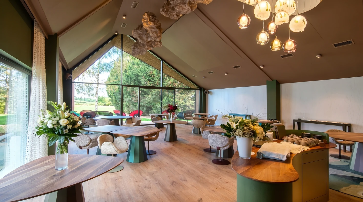 Salle de restaurant gastronomique lumineuse, toit en pente avec verrière triangulaire offrant vue sur parc arboré